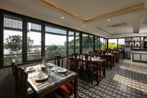 Nam Hai Hotel في هانوي: غرفة طعام مع طاولات وكراسي ونوافذ