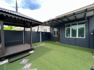 a patio of a house with green grass at Cozy Beach Getaway in Kampong Baharu Cherating