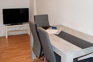 a dining table with chairs and a television in a room at Work & Stay in Hagen in Hagen