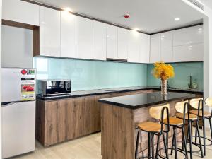 a kitchen with white cabinets and a counter with stools at HiSea Nha Trang in Nha Trang