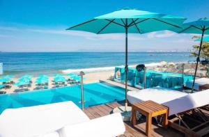 een zwembad met stoelen en een parasol en het strand bij Grant's Studio at Mantamar Tower in Puerto Vallarta