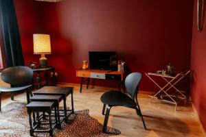 un soggiorno con pareti rosse, tavolo e sedie di Le rétro chic - Grand Duplex pour 6 dans le centre a Liegi