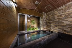 una piscina en una habitación con una pared de ladrillo en Almeria Hotel en Yamanakako