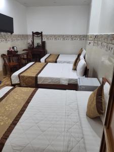 1 dormitorio con 2 camas y mesa en Sơn Tùng Motel, en Ấp Trà Kha