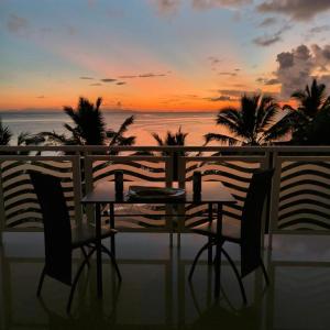 a table and chairs on a balcony with a sunset at Diamond Plaza in Grand Anse