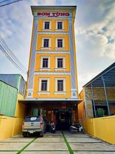 um edifício amarelo com um carro estacionado em frente em Sơn Tùng Motel em Ấp Trà Kha