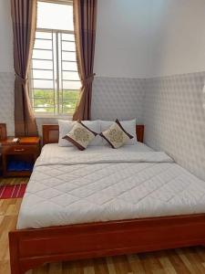 Schlafzimmer mit einem Bett mit weißer Bettwäsche und einem Fenster in der Unterkunft Sơn Tùng Motel in Ấp Trà Kha
