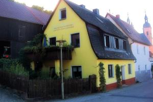 a yellow house with a black roof on a street at NEU! Ferienhaus am Klostergarten Gössweinstein in Gößweinstein