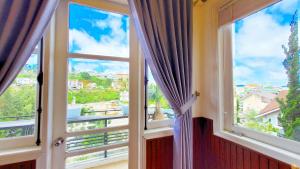 a room with two windows with views of a city at Villa H Flower Đà Lạt in Da Lat