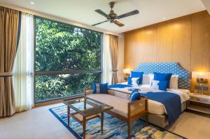 The Astor - All Suites Hotel Candolim Goa في كاندوليم: غرفة نوم بسرير ازرق ونافذة كبيرة