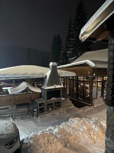 a building with a fireplace in the snow at Садиба MISHEL in Yablunytsya