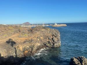een rotsachtige kustlijn met een brug in de oceaan bij Barista Homes in San Miguel de Abona