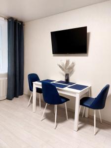 un comedor con una mesa blanca y sillas azules en Свежая 2-комнатная квартира в центре, en Khmelʼnytsʼkyy