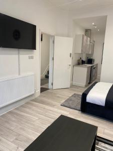 a white bedroom with a bed and a kitchen at Holiday Plus - Palatine Road in Blackpool