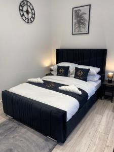 a black bed with white sheets and a clock on the wall at Holiday Plus - Palatine Road in Blackpool
