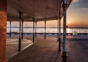 a view of the ocean from a pier at sunset at Black Pearl Apartment New Brighton in Wallasey