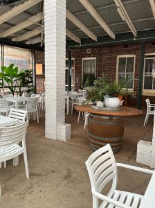 un patio con sillas blancas, mesa y mesas en THE FED AND BED TEMORA, en Temora
