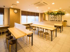 um restaurante com mesas e bancos e um relógio em Super Hotel Kitami em Kitami