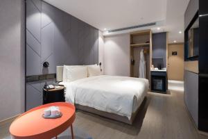 a bedroom with a bed and a table and a kitchen at Atour S Hotel Guangzhou Tianhe Taikoo Hui in Guangzhou