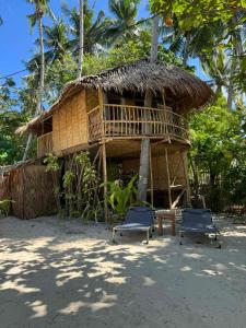 a house with two chairs and a straw roof at Bice Camp Darocotan in El Nido