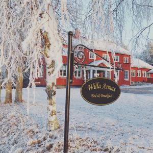 un panneau dans la neige devant un bâtiment dans l'établissement Bed & Breakfast Willa Armas, à Övertorneå