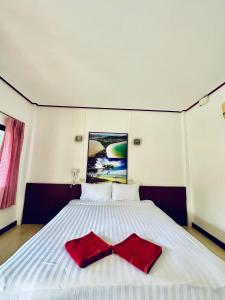 een wit bed met een rode strik erop bij Lanta L.D. Beach Bungalow in Koh Lanta