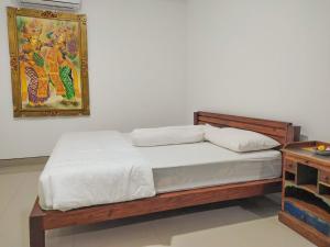 a bed in a bedroom with a painting on the wall at Pondok Selip Guesthouse in Krambitan +12 photos