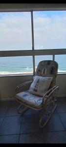 a chair sitting in front of a window with the ocean at 703 High Tide, Holiday Apartment, Main Beach, Amanzimtoti in Amanzimtoti