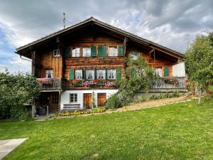 a wooden house with a green lawn in front of it at Alpenchalet Haldeli Gstaad Ferienwohnung im 1-Stock in Gstaad
