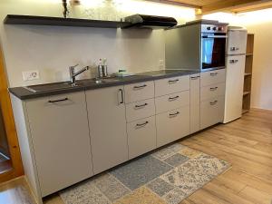 a white kitchen with a sink and a refrigerator at Alpenchalet Haldeli Gstaad Ferienwohnung im 1-Stock in Gstaad