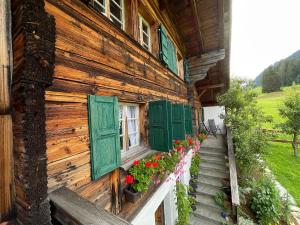 een huis met groene luiken en bloemen op de veranda bij Alpenchalet Haldeli Gstaad Fereienwohnung im 1-Stock in Gstaad