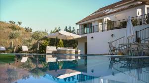 a swimming pool with an umbrella and a house at Mountain Retreat in Troodos