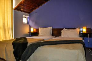 2 camas en un dormitorio con una pared azul en Bela Sombra en Vila da Ribeira Brava
