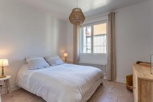 a bedroom with a white bed and a window at Le Carrousel - Appartement avec studio attenant in Deauville