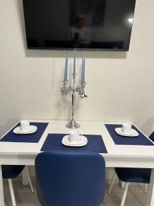 una mesa azul y blanca con 2 velas y sillas azules en Свежая 2-комнатная квартира в центре, en Khmelʼnytsʼkyy