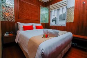 a bedroom with a large bed with red pillows at PETIT BOUTIQUE HOTEL SOLO in Solo