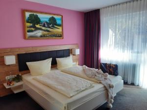 a bedroom with a white bed with a pink wall at Schwarzwaldhotel Sonne in Baden-Baden