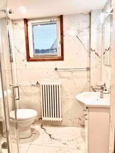 La salle de bains est pourvue de toilettes, d'un lavabo et d'une fenêtre. dans l'établissement Mountain View Apartment, à Kandersteg