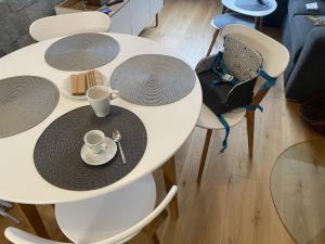 uma mesa branca com pratos, chávenas e cadeiras em Apartmány Vodohospodár em Mýto pod Ďumbierom