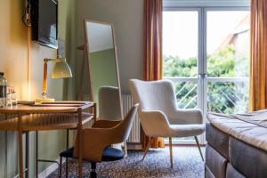 ein Hotelzimmer mit einem Schreibtisch, Stühlen und einem Fenster in der Unterkunft Hotel Tønderhus in Tønder