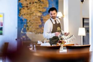 Ein Mann, der an einem Tisch steht und Wein gießt. in der Unterkunft Hotel Tønderhus in Tønder