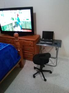 a bedroom with a television and a desk with a laptop at Hunts Point Short Stays in Hunts Point