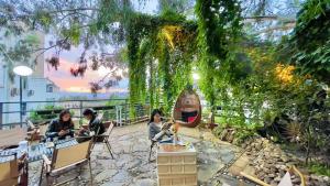 昆明Kunming Upland International Youth Hostel ,near the city center ,2 mins walk to the subway, 2 mins walk to the Green Lake, Close to Yuan tong Temple, Old street, Yunnan University, convenient payment and visa cards are accepted的一群人坐在树下的椅子上 更多37张照片