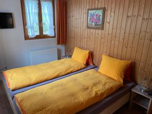 1 dormitorio con 2 camas con sábanas amarillas y ventana en Alpenchalet Spiher Gstaad Ferienwohnung im Parterre, en Gstaad