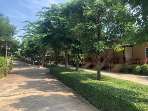 a tree lined street in front of a building at วังอินธารา รีสอร์ท (Wangintara Resort) in Phitsanulok +5 photos