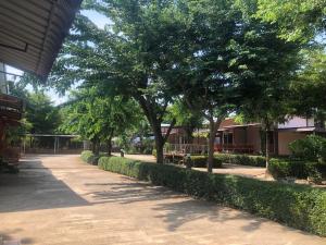 a walkway with trees and bushes next to a building at วังอินธารา รีสอร์ท (Wangintara Resort) in Phitsanulok