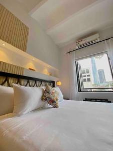 ein Schlafzimmer mit einem großen weißen Bett mit einem Fenster in der Unterkunft Daniel's Studio in Saigon Center with Hot tub and View in Ho-Chi-Minh-Stadt