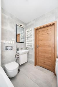 baño con aseo, lavabo y puerta en Komfortowe Apartamenty z Garażem na Milionowej, en Łódź