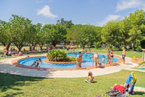 un groupe de personnes dans une piscine dans un parc dans l'établissement Ecològic Vinyols Camp, à Vinyols i els Arcs