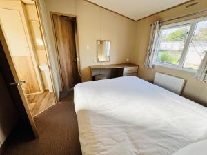 - une petite chambre avec un lit blanc et une fenêtre dans l'établissement 2 Bedroom Caravan CW111, Whitecliff Bay, Bembridge, Isle of Wight, à Bembridge